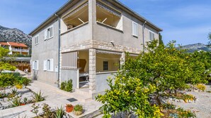 Ein zweistöckiges Haus mit Balkon, Steinaußenwand und einem Garten mit verschiedenen Pflanzen.