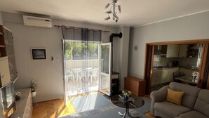 Ein modernes Wohnzimmer mit einer Couch, einem Couchtisch und einem Essbereich. Ein Schiebeglasfenster führt zu einem Balkon.
