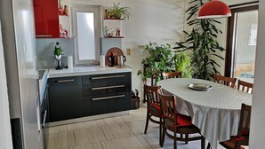 Eine moderne Küche mit Essbereich, ausgestattet mit einer weißen Arbeitsplatte, schwarzen Schränken und einem runden Tisch mit Stühlen.