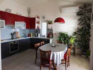 Une cuisine moderne avec des meubles de rangement rouges, une table à manger avec des chaises et divers appareils de cuisine.
