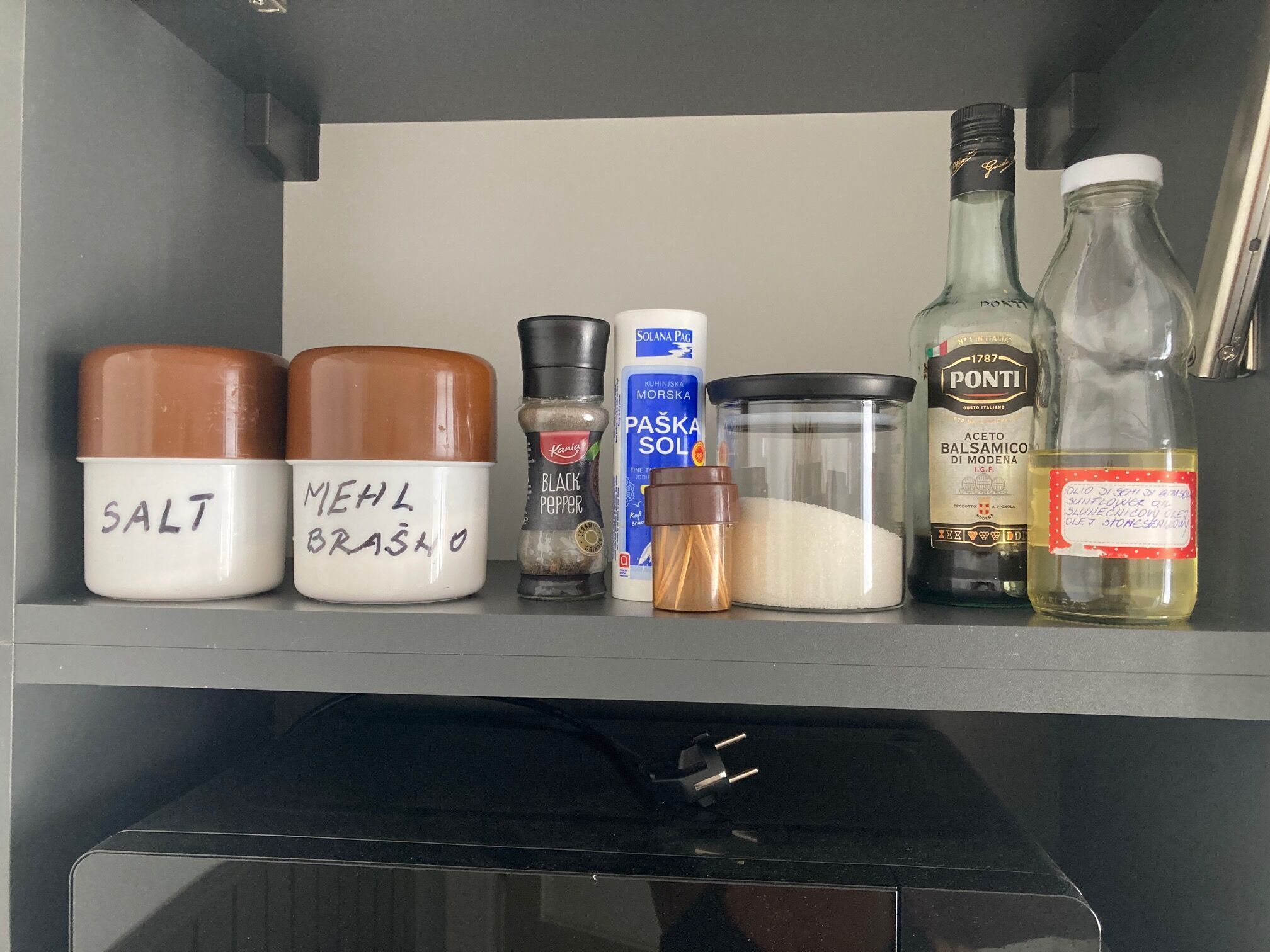 En hyld i et køkken med salt, mel, sort peber, pasta og en flaske aceto balsamico di modena.