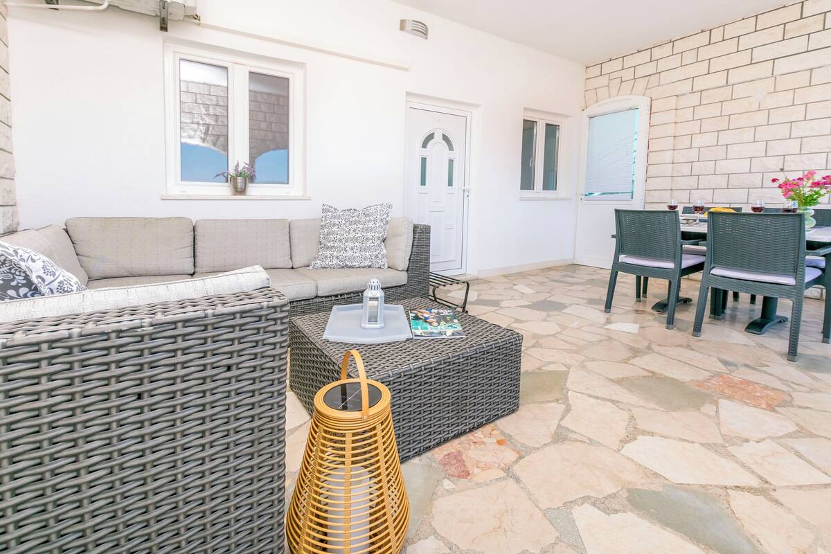A cozy outdoor seating area with a wicker sofa, a small table, and a wicker basket.