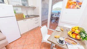Une cuisine avec des meubles blancs, un évier et un coin repas avec une table mise pour deux personnes.