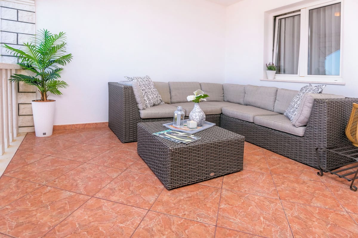 A living room with a sectional sofa, a coffee table, a potted plant, and a window with curtains.
