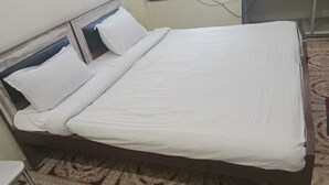 Un letto rifatto con lenzuola bianche in una stanza con tappeto a motivi.