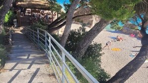 Ein Weg, der zu einem Strand führt, mit einer Geländer auf einer Seite und Bäumen auf der anderen.