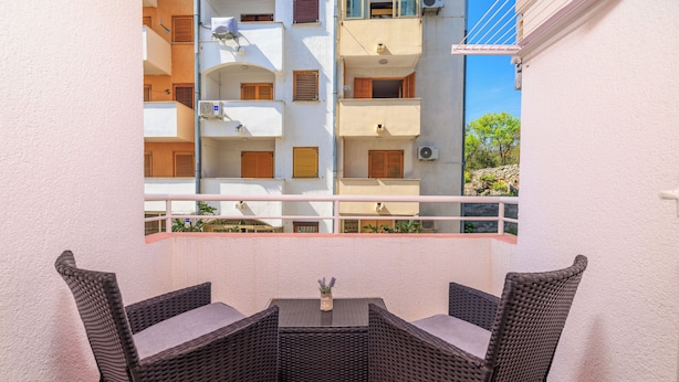 A balcony with wicker furniture and a view of adjacent buildings. - Apartment Roli (Crikvenica)