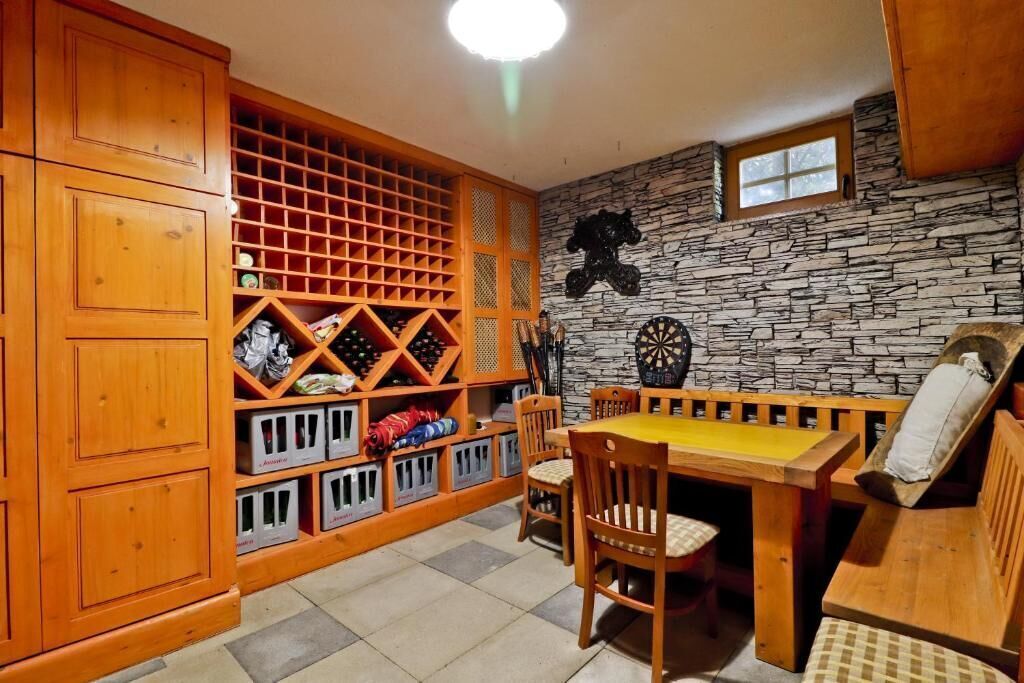 Un comedor de madera con pared de piedra, una mesa, sillas y un banco.