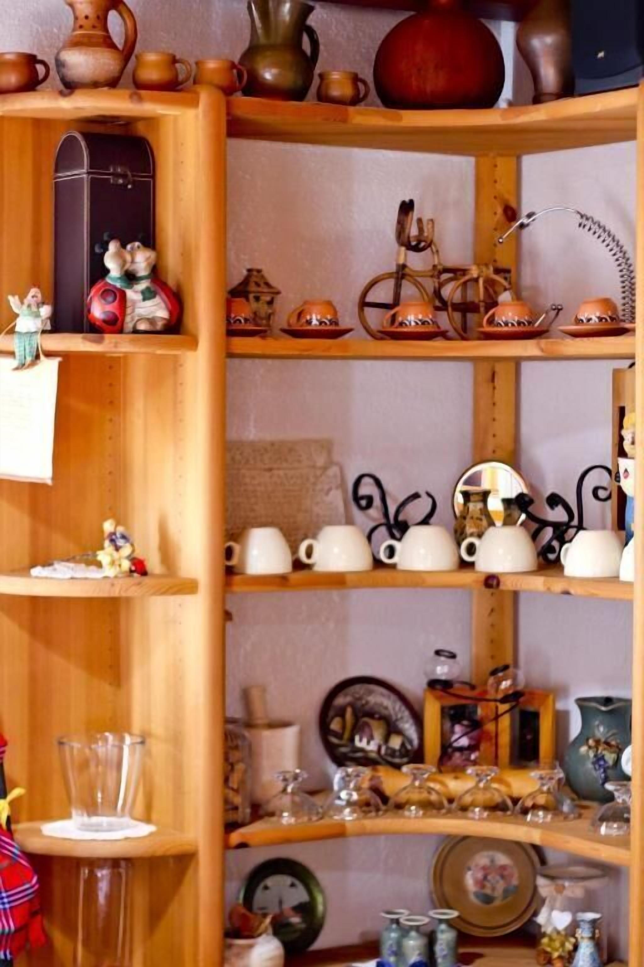A wooden shelf with various ceramic items, including mugs, teapots, and decorative plates.
