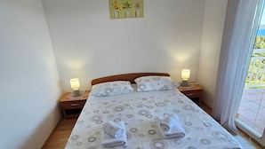 A neatly made bed with a patterned bedspread, two bedside lamps, and a painting of flowers on the wall. - Apartments Sea and Pine (Jelsa)