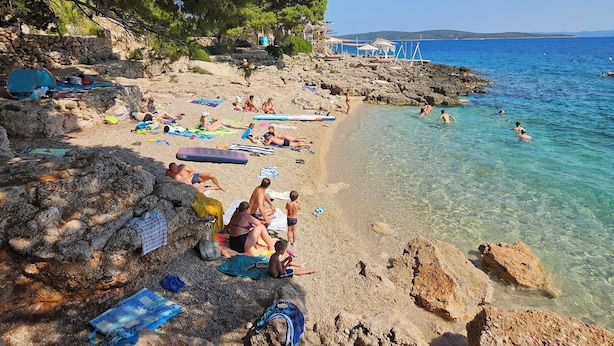 A beach with clear water, people sunbathing, and some swimming. - Apartments Sea and Pine (Jelsa)