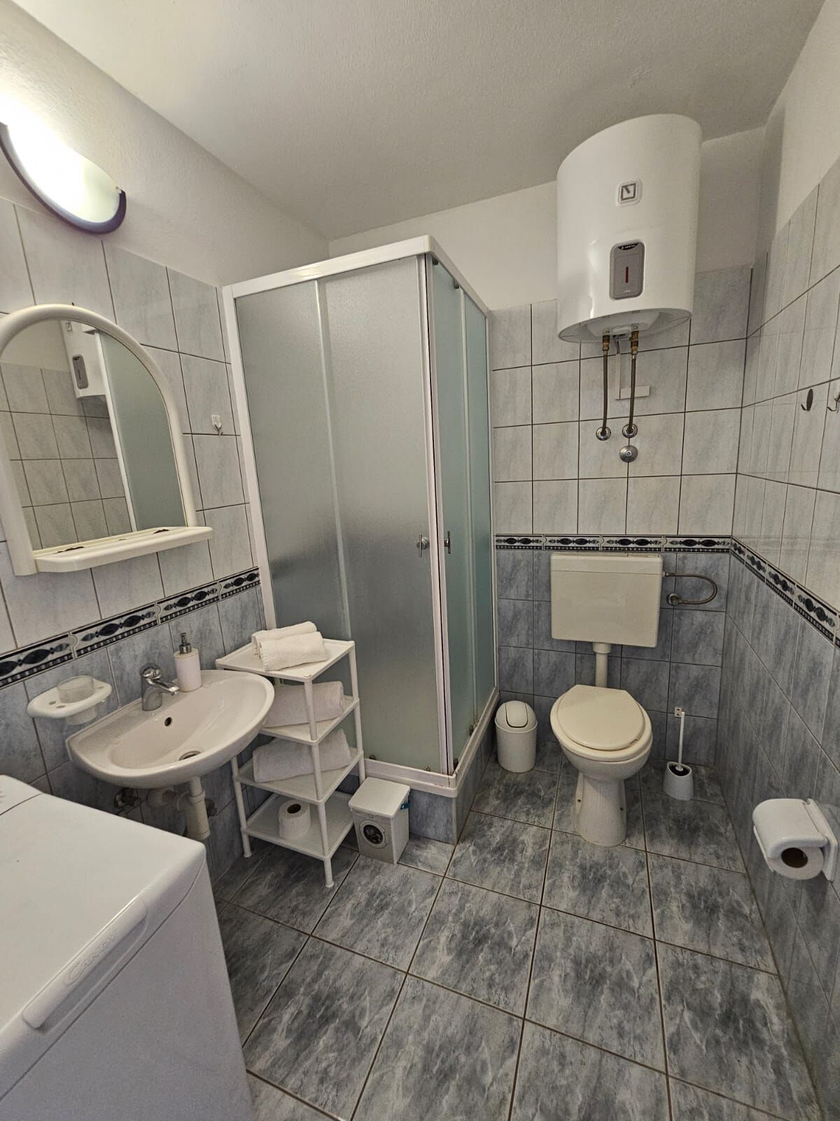 Un baño moderno con cabina de ducha, inodoro, lavabo y espejo.