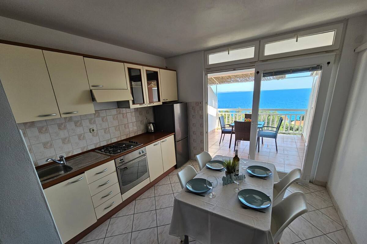 A kitchen with a dining area overlooking the sea.