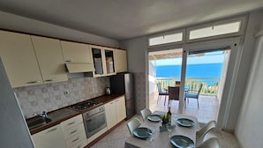 A kitchen with a dining area overlooking the sea. - Apartments Sea and Pine (Jelsa)