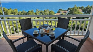 A balcony with a table set for breakfast, overlooking a coastal view. - Apartments Sea and Pine (Jelsa)