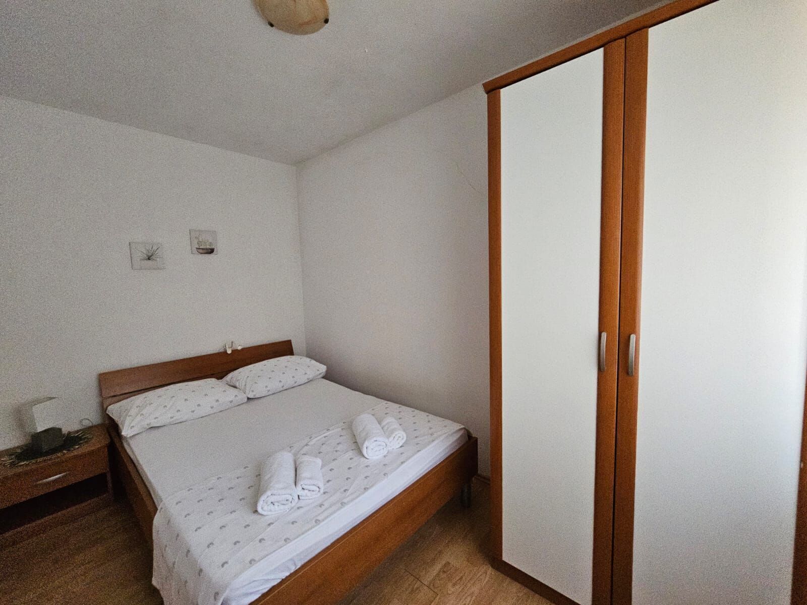 A bedroom with a wooden bed, a wardrobe, and a nightstand.
