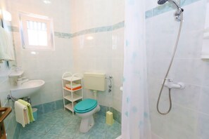 A bathroom with a toilet, sink, shower, and a window. - Apartments Vacation Jakisnica (Novalja)