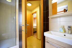 Un baño con ducha, lavamanos y espejo.