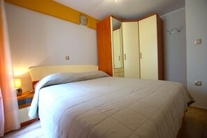 Un dormitorio con cama, mesita de noche, armario y espejo.