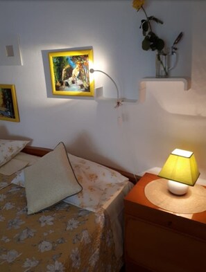 A bedroom with a bed, a bedside lamp, a framed picture on the wall, and a small plant on a shelf. - Apartment Apartment Yellow (Baska Voda)