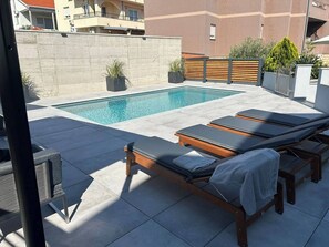 Una piscina al aire libre, sombrillas, tumbonas