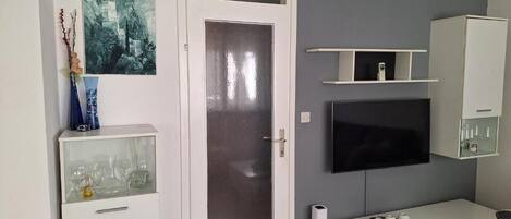 Una sala de estar moderna con un ventanal, un televisor montado, un mueble blanco y una consola.
