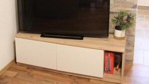 Un televisor de pantalla plana sobre un mueble de madera frente a una pared de piedra.
