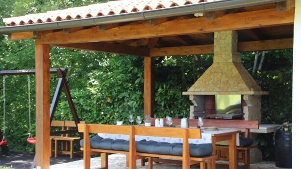 Un patio al aire libre con muebles de madera, una chimenea de piedra y un columpio.