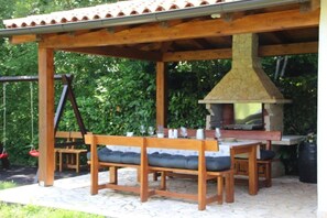 Un patio al aire libre con muebles de madera, una chimenea de piedra y un columpio.