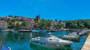 A marina with boats docked, a clear blue sky, and a town with buildings and a church in the background. - Apartment New (Supetar)