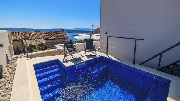 A rooftop swimming pool with a view of the sea, a tiled roof, and a white wall. - House Emma (Crikvenica)