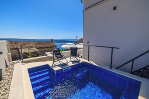 Una piscina al aire libre, sombrillas, sillones reclinables de piscina