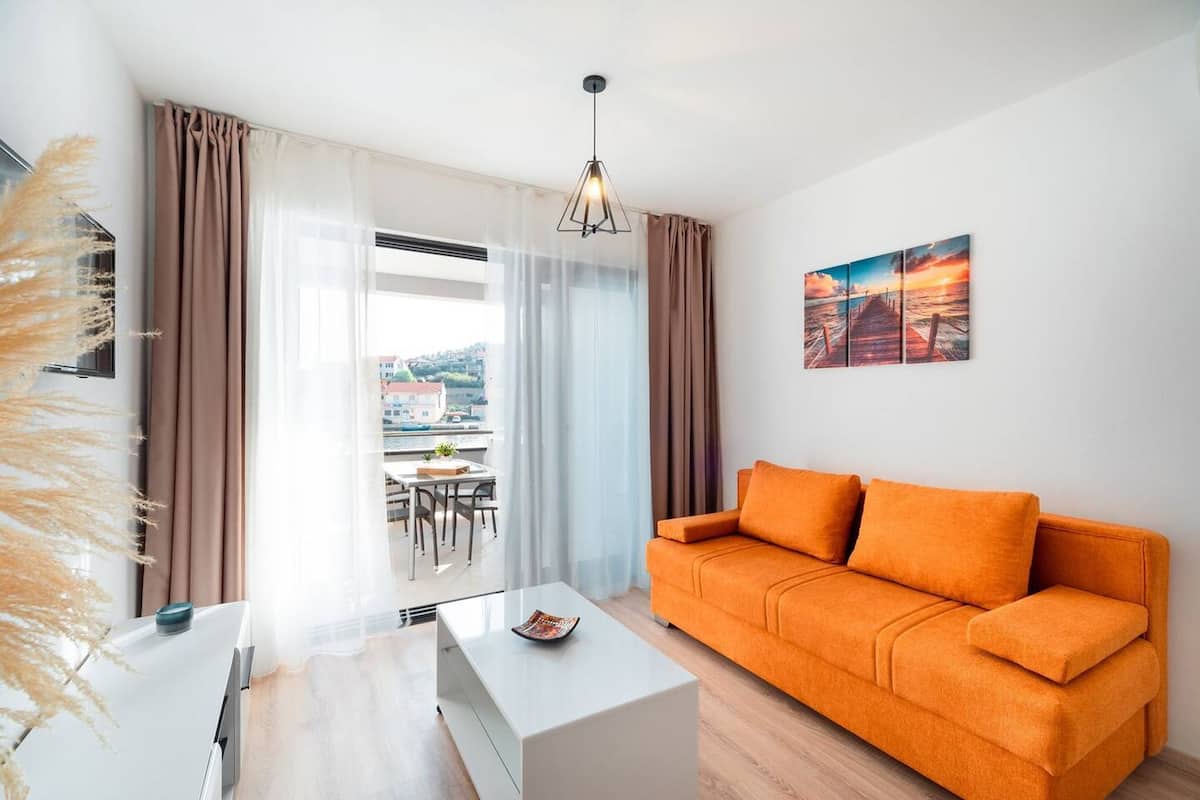 Un salon moderne avec un canapé blanc, une table basse en verre et une vue sur un balcon.
