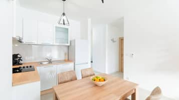 Et moderne køkken med hvide skabe, en træbordplade og et spisebord med en skål med frugt.