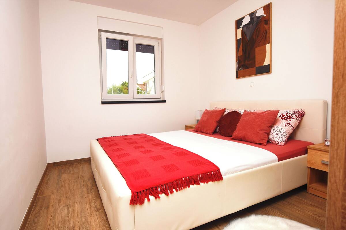 Une chambre à coucher avec un lit, une fenêtre, une table de chevet et un tableau accroché au mur.