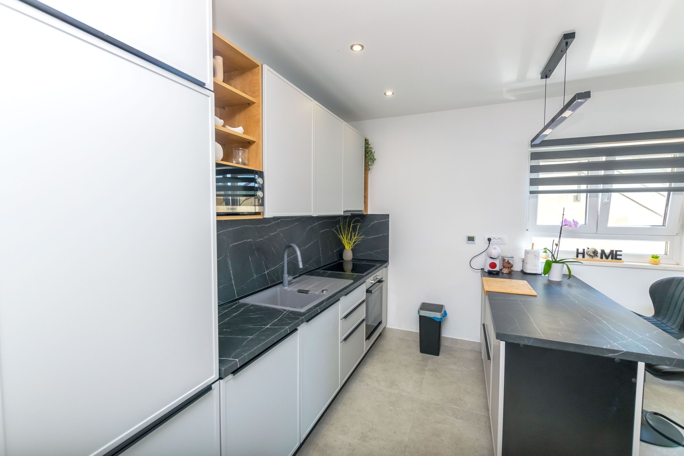 A modern kitchen with black countertops, white cabinets, and a built-in oven.
