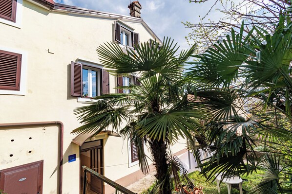 A building with multiple windows and a palm tree in the foreground. - Apartment Volosko for two (Opatija)