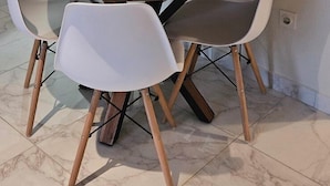 A dining area with a round wooden table, two white chairs, and a clock on the wall. - Apartments Madeji (Rab)