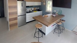A modern kitchen with a wooden island, bar stools, a refrigerator, and a TV mounted on the wall. - House Holiday Lodge (Sibenik)