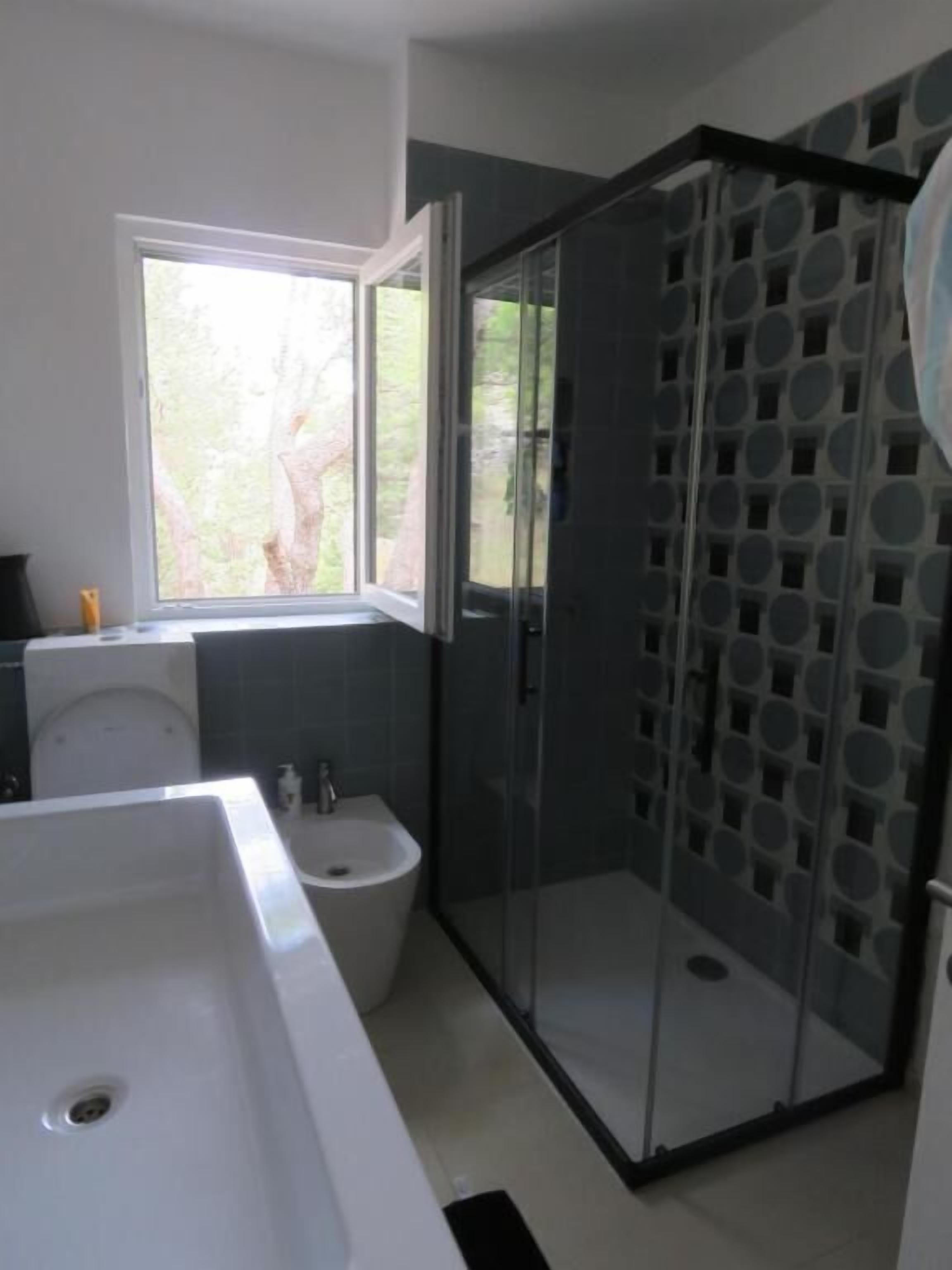 A modern bathroom with a large white sink, a toilet, and a glass-enclosed shower.