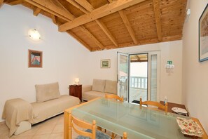 Ein gemütliches Zimmer mit einem Glastisch, zwei Sofas, einer Holzbalkendecke und einer Glastür, die zu einem Außenbereich führt.