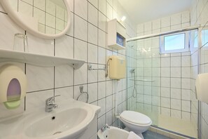 A bathroom with a sink, mirror, toilet, and glass shower enclosure. - Apartments Jany (Mljet)