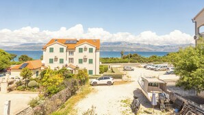 A coastal building with a view of the sea, parked cars, and a caravan. - Apartment Vinka (Supetar)