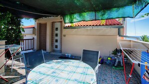 Un patio cubierto con una mesa, sillas, un tendedero y una puerta con ventanal.