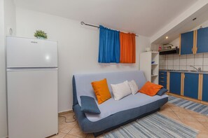 A compact living space with a sofa, a small kitchenette, and a white refrigerator. - Apartments Marija (Vodice)