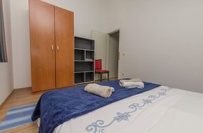 A bedroom with a bed, a wardrobe, a shelf unit, and a chair. - Apartments Marija (Vodice)