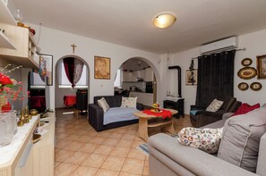 A living room with a sofa, a dining table, and a kitchen in the background. - Apartments Marija (Vodice)