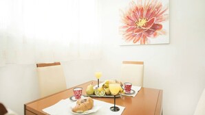 Een ontbijttafel compleet met een croissant, fruit en sap, en een groot bloemenkunstwerk aan de muur.