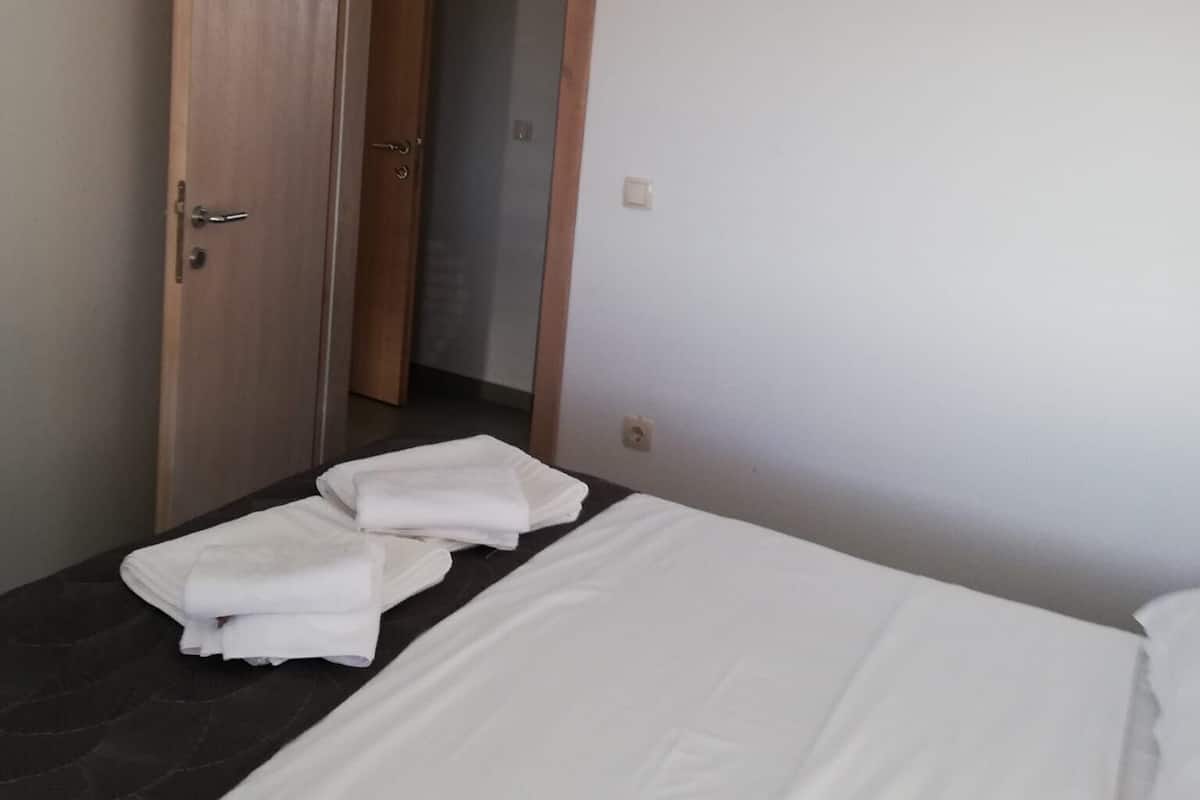 Une chambre d’hôtel avec un lit, une porte en bois, un appareil de climatisation et une serviette sur le lit.