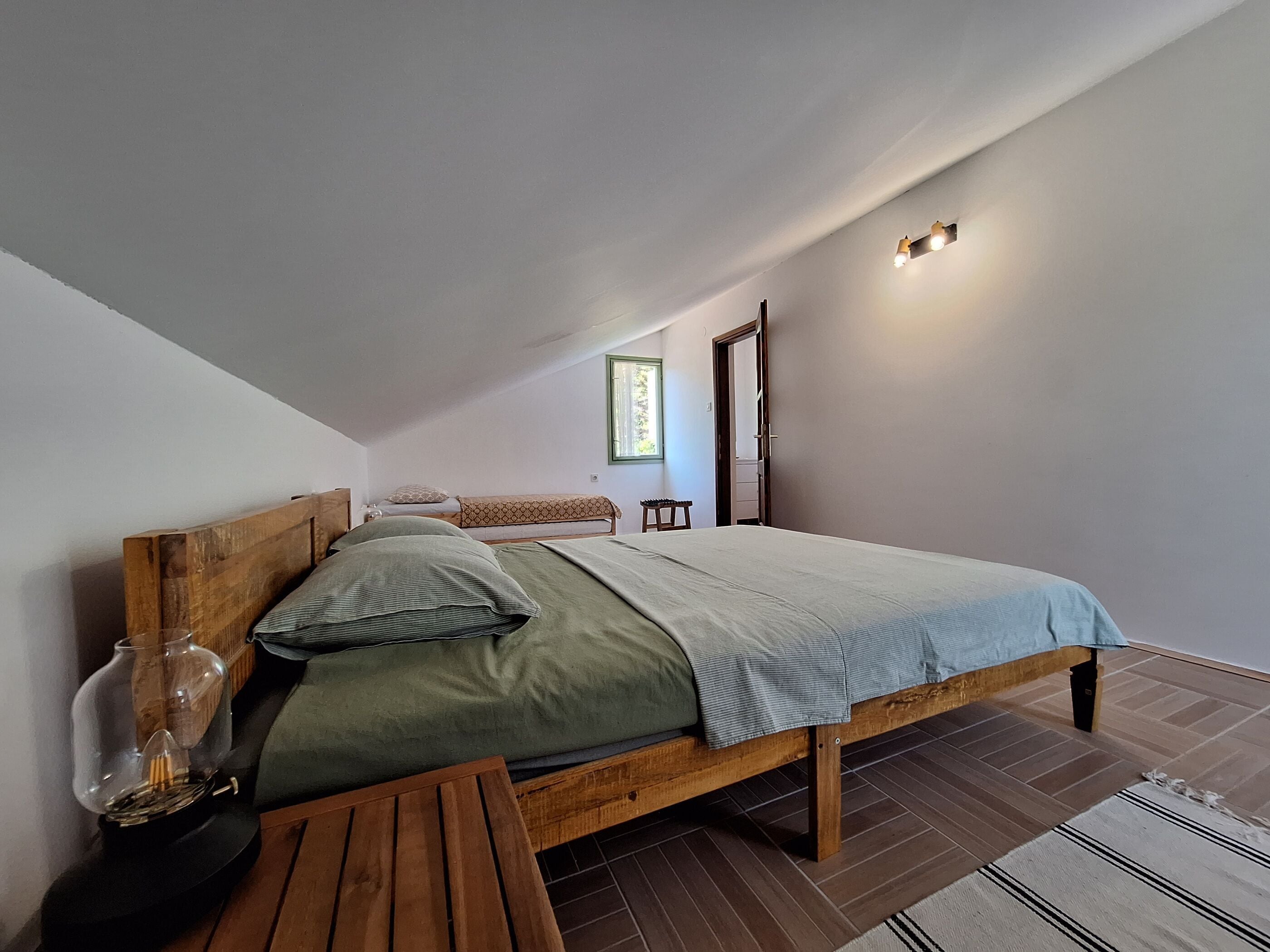 A bedroom with a wooden bed, a small table, and a lamp.